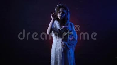 年轻孤独的死去的新娘的幻影站着悲伤的脸，手里拿着花。 恐怖女孩万圣节化妆
